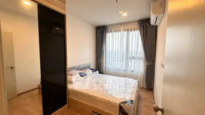 Modern bedroom with large window and stylish decor in a contemporary apartment.