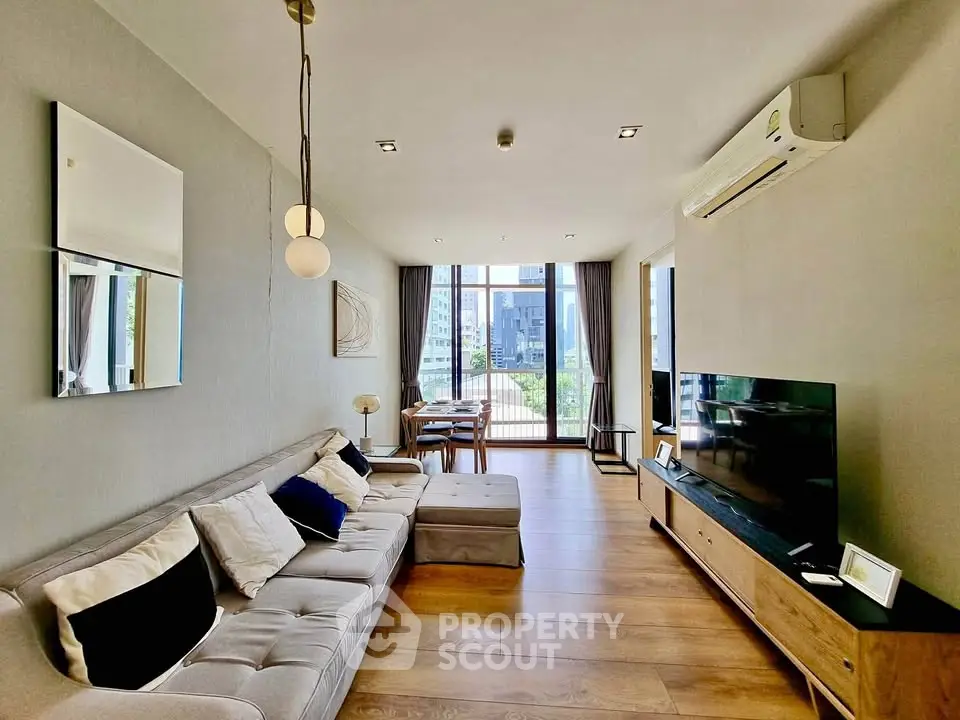 Spacious modern living room with large windows and stylish decor in a high-rise apartment.
