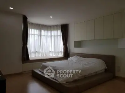Spacious bedroom with modern design and large window seating area.