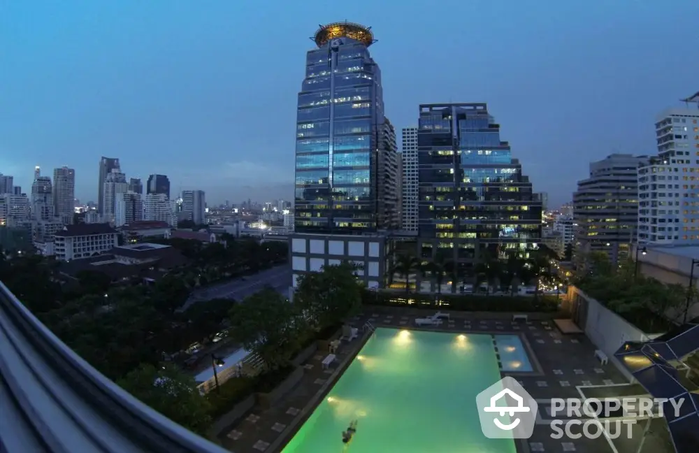 Stunning cityscape view with illuminated pool and modern high-rise buildings at dusk.