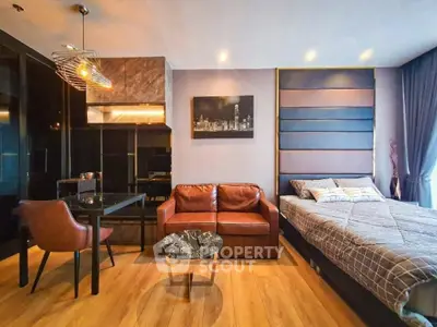 Modern studio apartment with stylish decor, featuring a cozy bed, leather sofa, and elegant dining area.