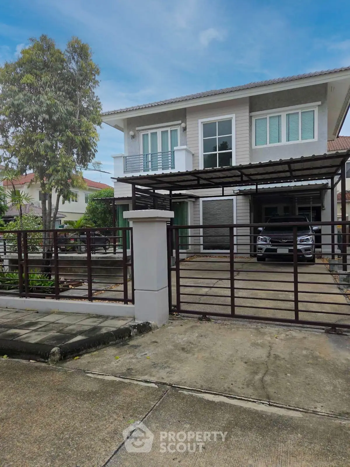 Modern two-story house with gated driveway and carport in suburban neighborhood.