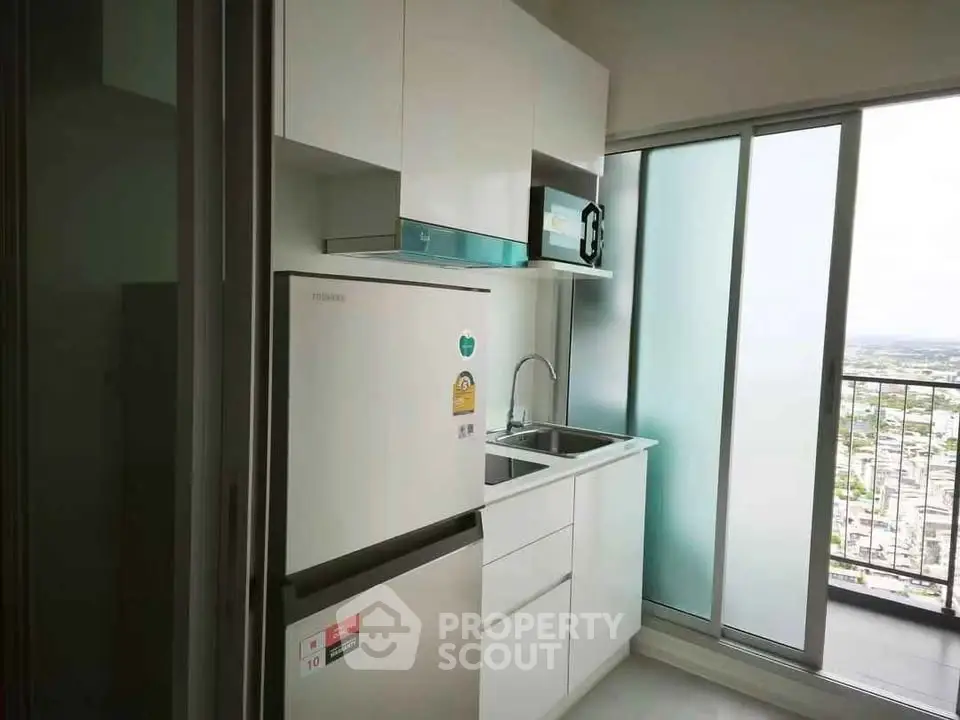 Modern kitchen with sleek appliances and balcony view in high-rise apartment.