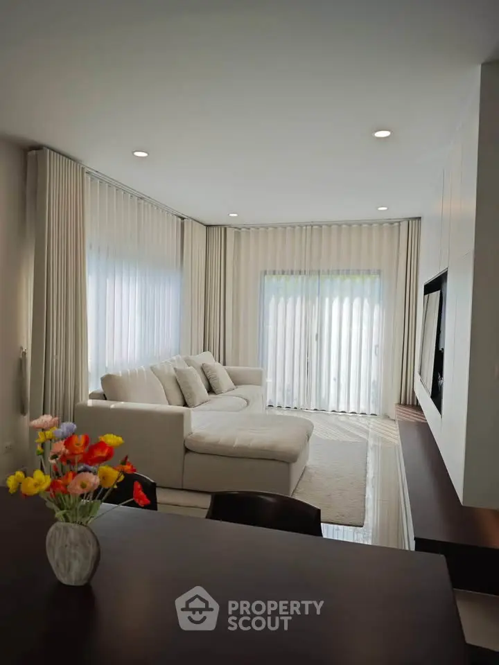 Elegant living room with large windows and cozy white sofa, perfect for relaxation and entertaining.
