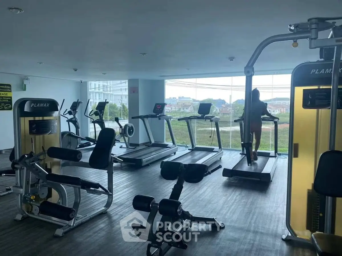 Spacious gym with modern equipment and scenic view, ideal for fitness enthusiasts.