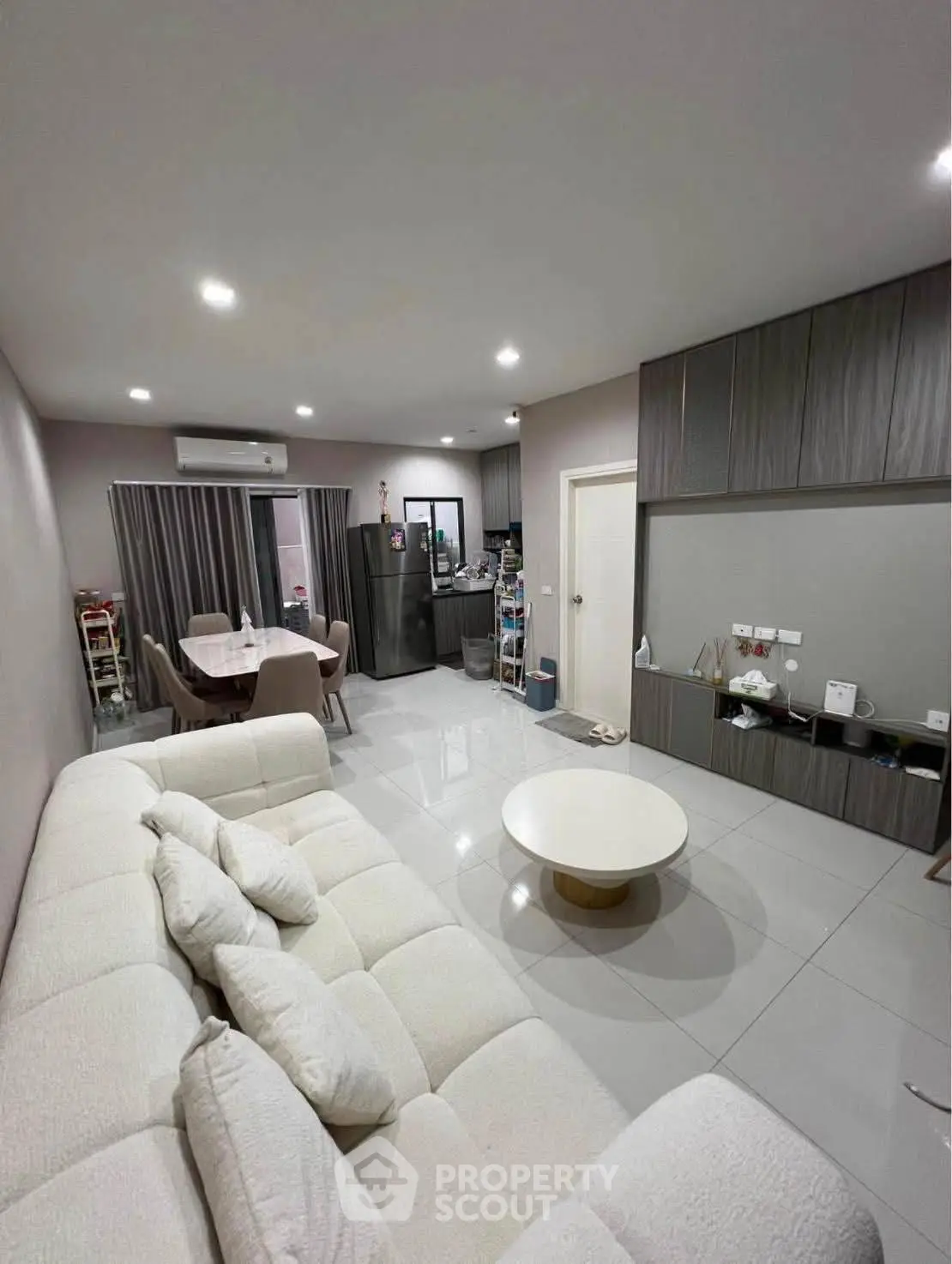 Modern living room with cozy sofa, sleek cabinetry, and dining area in open layout apartment.
