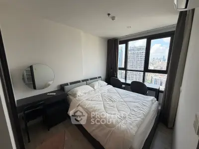 Modern bedroom with city view, featuring sleek furniture and large windows for natural light.