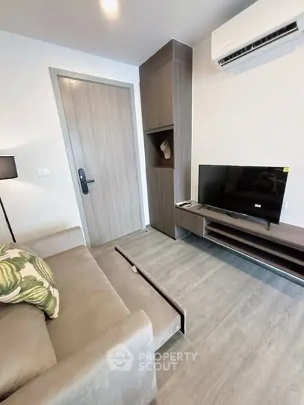 Modern living room with sleek furniture and wall-mounted TV, featuring a cozy sofa and stylish decor.