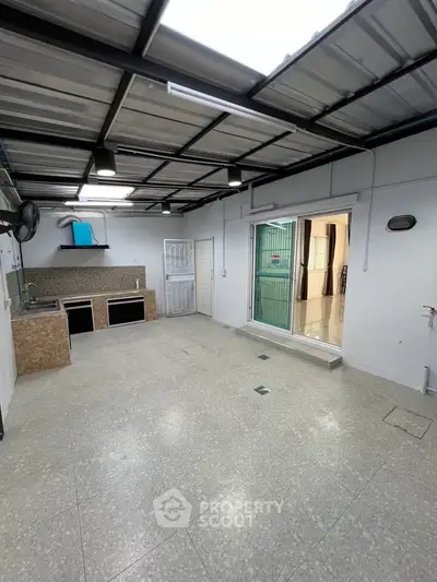 Spacious covered outdoor area with modern kitchen setup and sliding glass doors.