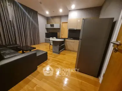 Modern open-layout living room with sleek kitchen and hardwood floors