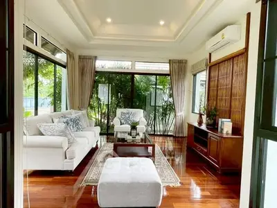 Elegant living room with large windows and stylish decor, featuring hardwood floors and cozy seating.