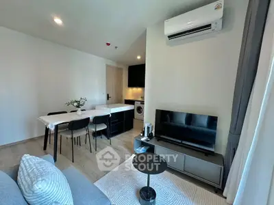 Modern living room with dining area and kitchen featuring sleek design and air conditioning.