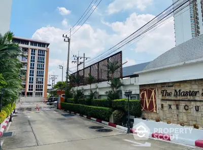 Modern condominium entrance with lush greenery and clear blue sky