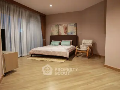 Spacious bedroom with modern decor and large window for natural light.