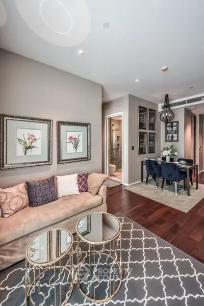 Elegant living room with stylish decor and dining area, featuring plush sofa and chic glass tables.