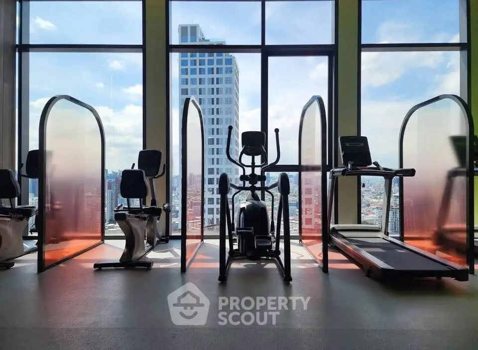 Modern gym with city view, featuring exercise bikes and treadmill in high-rise building.