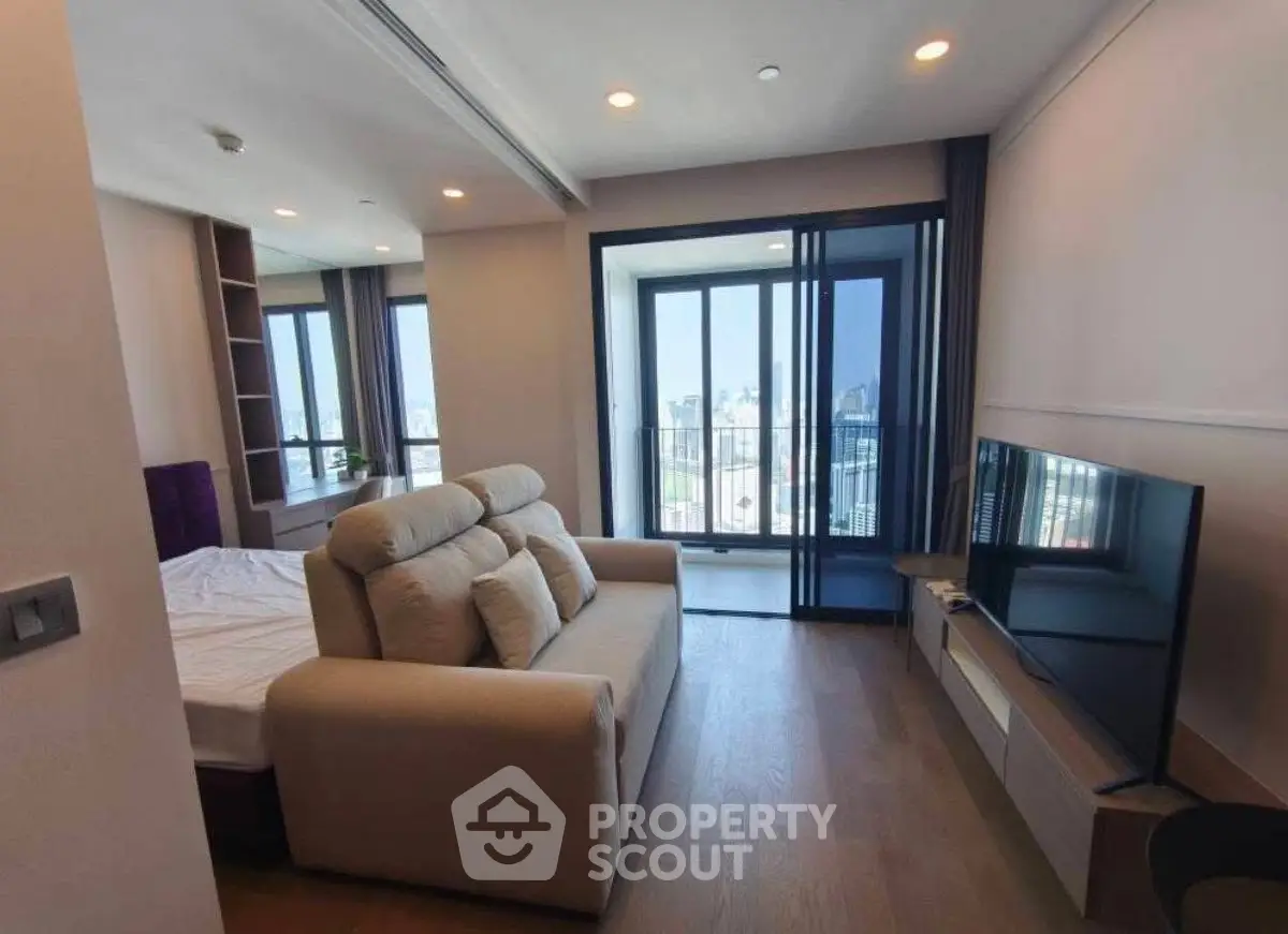 Modern living room with city view, featuring a cozy sofa and flat-screen TV, ideal for urban living.