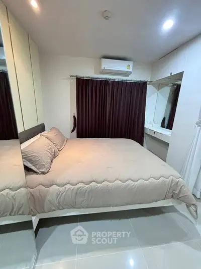Cozy bedroom with modern decor, featuring a comfortable bed, mirrored wardrobe, and air conditioning.