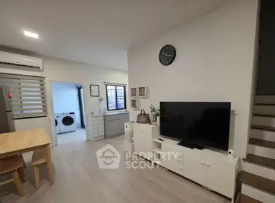 Modern living room with TV, dining table, and open kitchen layout