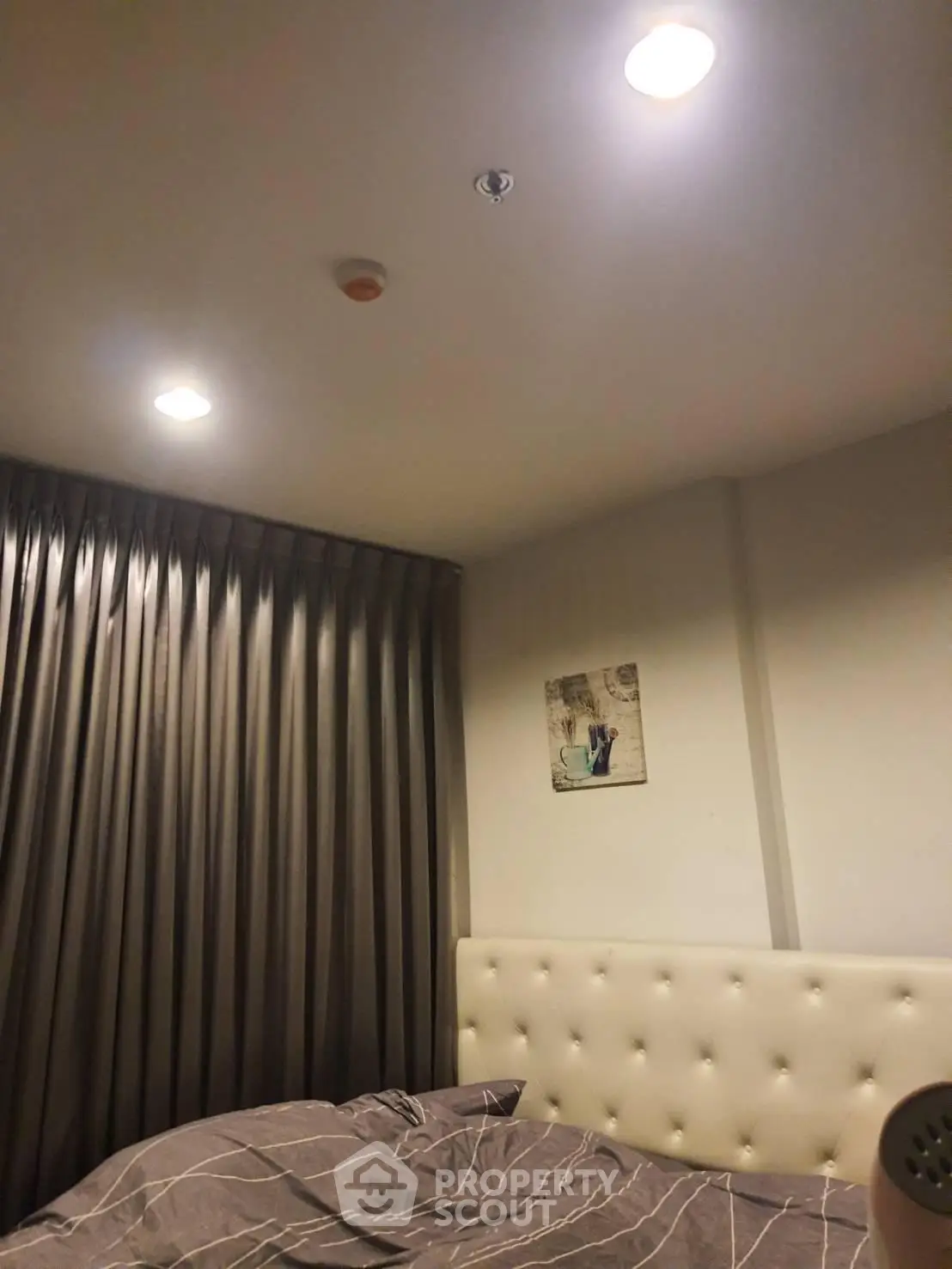 Cozy bedroom with elegant lighting and plush headboard, perfect for relaxation.