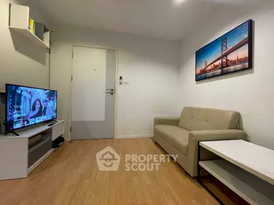 Cozy living room with modern decor and wooden flooring, featuring a comfortable sofa and flat-screen TV.