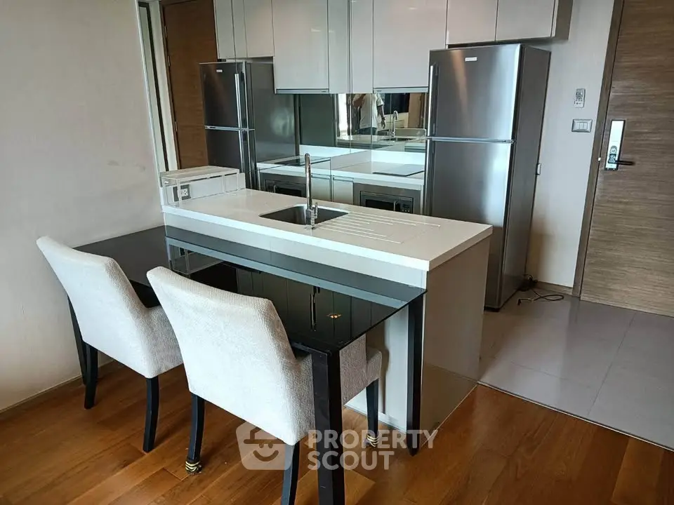 Modern kitchen with sleek appliances and stylish dining area in a contemporary apartment.