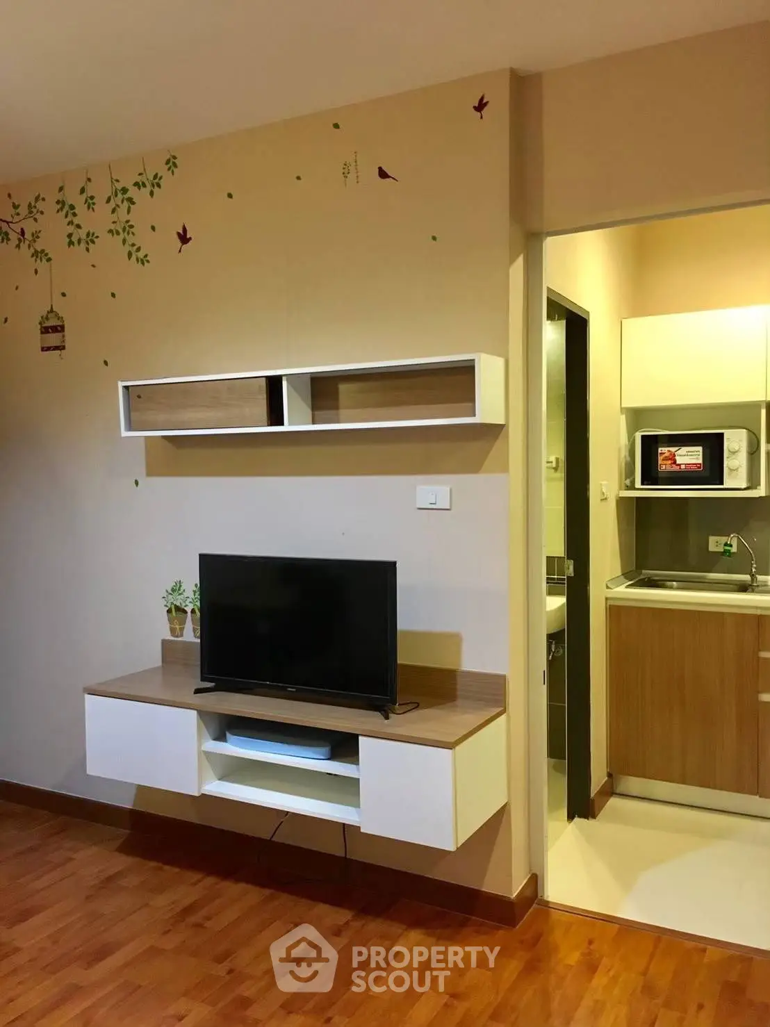 Modern living room with wall-mounted TV and compact kitchen area.