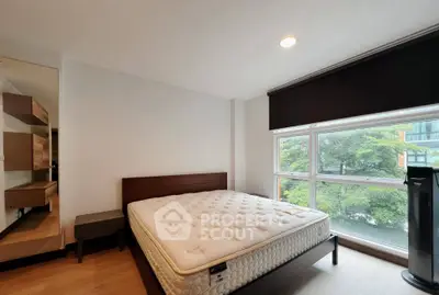 Spacious bedroom with large window and modern furnishings, offering a serene view.