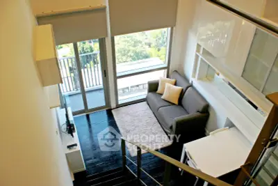 Modern loft-style living room with balcony and large windows offering a scenic view.