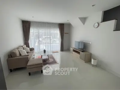 Spacious modern living room with sleek furniture and large window for natural light.