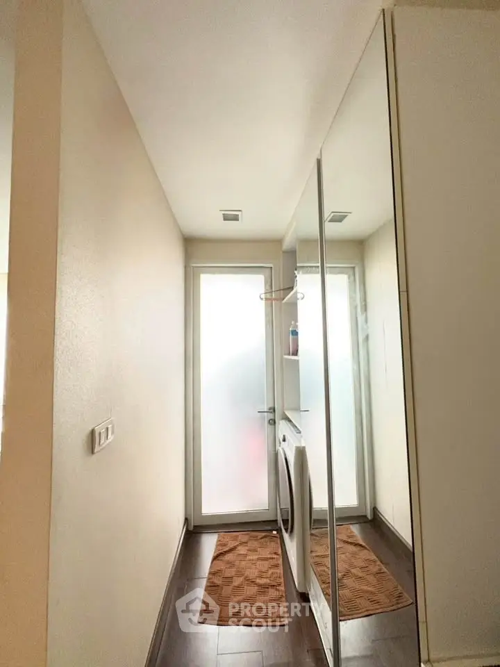 Modern laundry area with washing machine and frosted glass door, featuring sleek design and ample storage space.