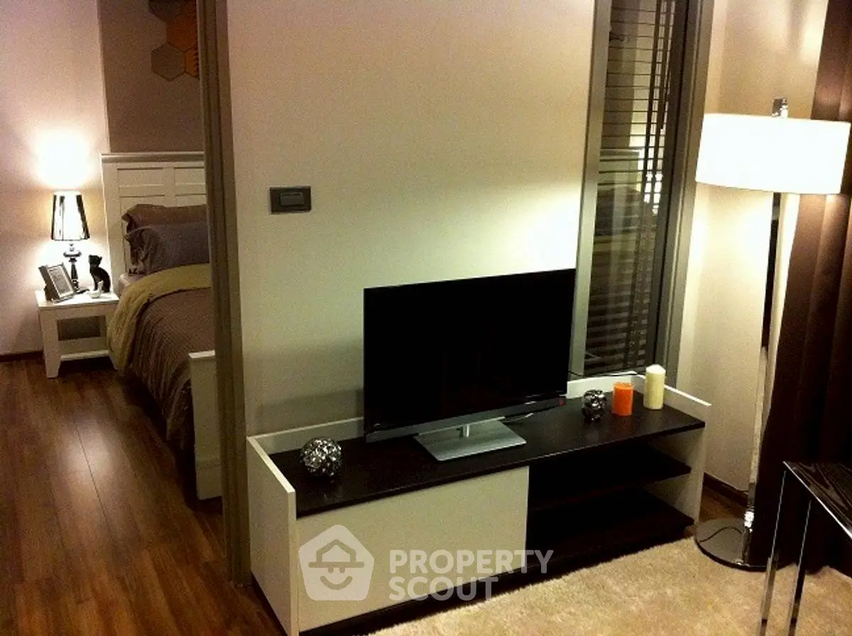 Modern living room with sleek TV stand and cozy bedroom view, perfect for urban living.