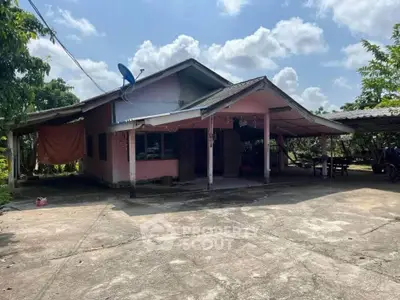Charming rural house with spacious driveway and lush greenery, perfect for serene living.