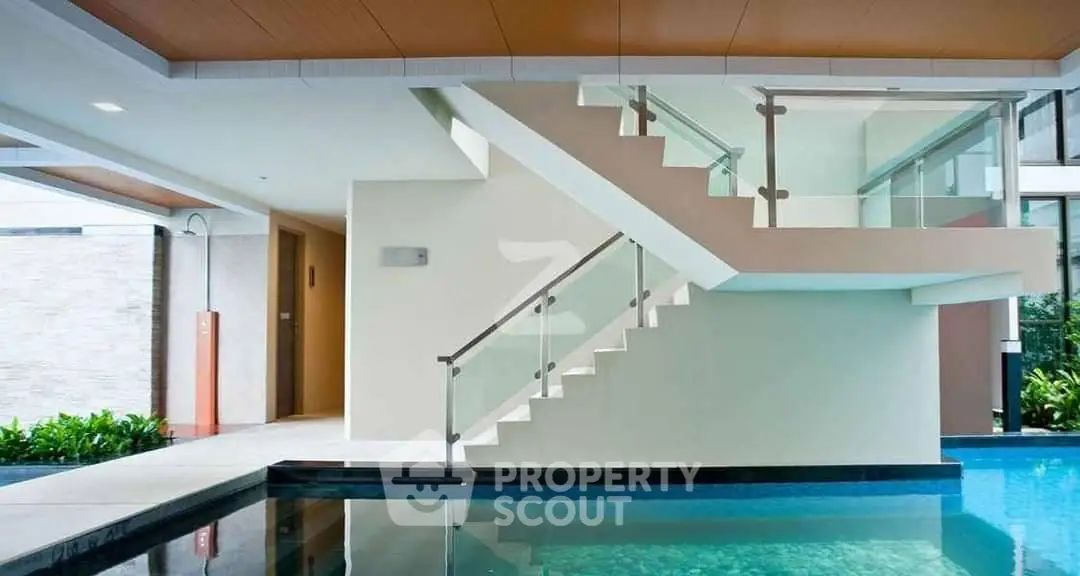Modern luxury poolside area with sleek staircase and glass railing in upscale property.