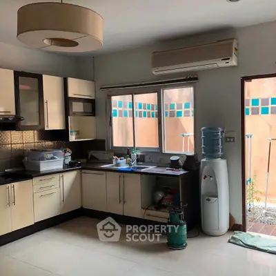 Spacious kitchen with modern cabinetry and natural light, featuring a water dispenser and air conditioning unit.
