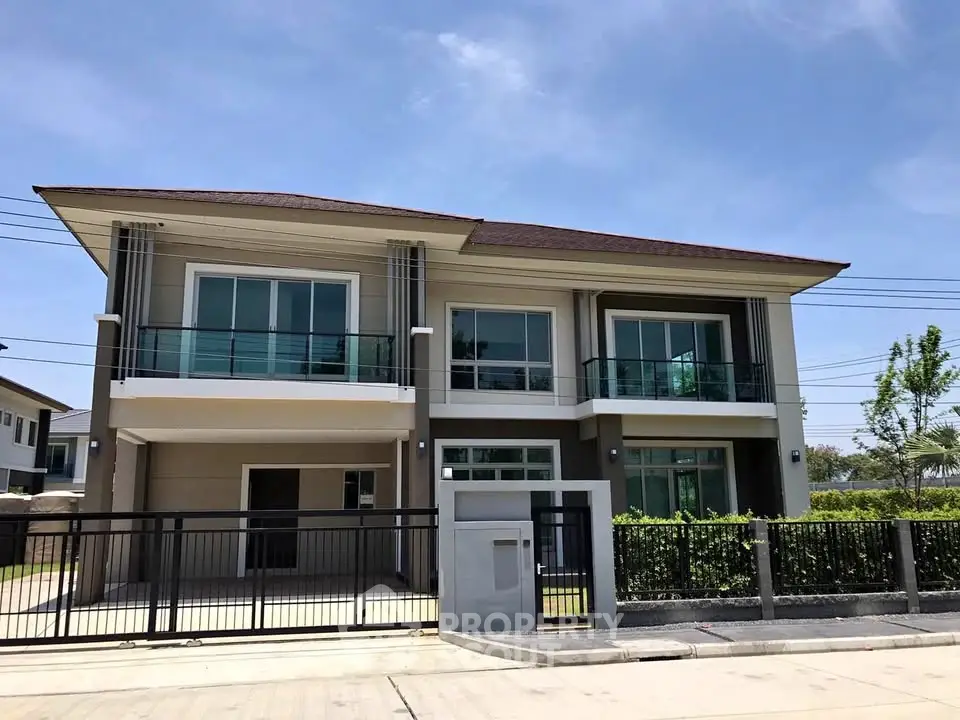 Modern two-story house with large windows and balcony in a suburban neighborhood.