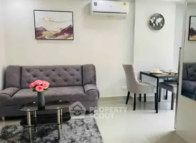 Modern living room with stylish sofa and dining area, featuring elegant decor and air conditioning.
