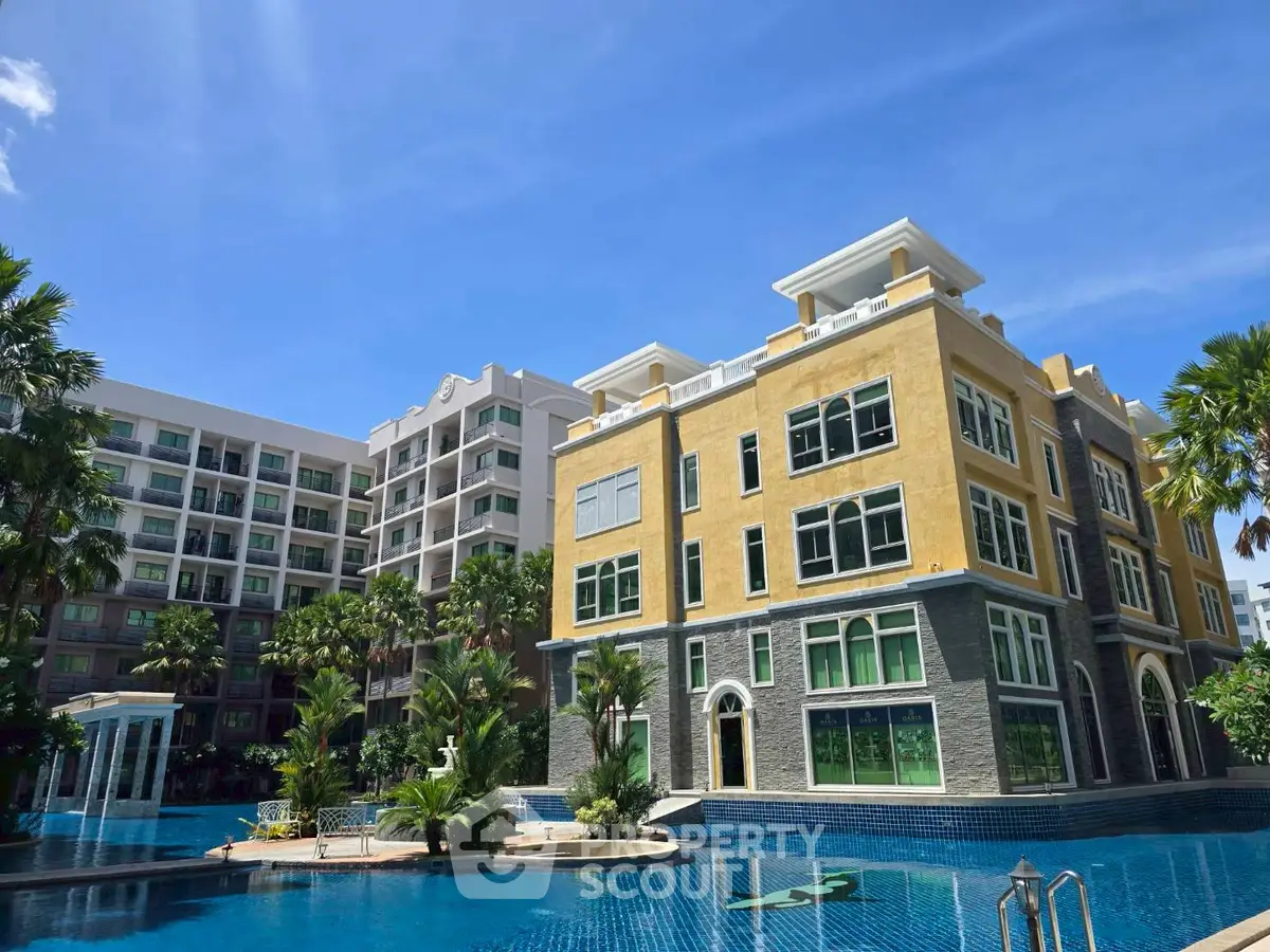Luxurious residential complex with stunning pool and modern architecture under clear blue sky.