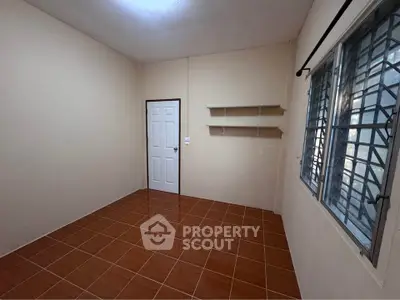 Spacious empty room with tiled floor and natural light from window