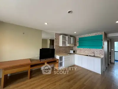 Modern open-plan kitchen and living area with wooden floors and brick accents.