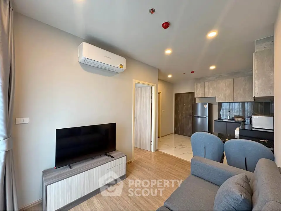 Modern living room with sleek kitchen, featuring stylish furniture and contemporary design.