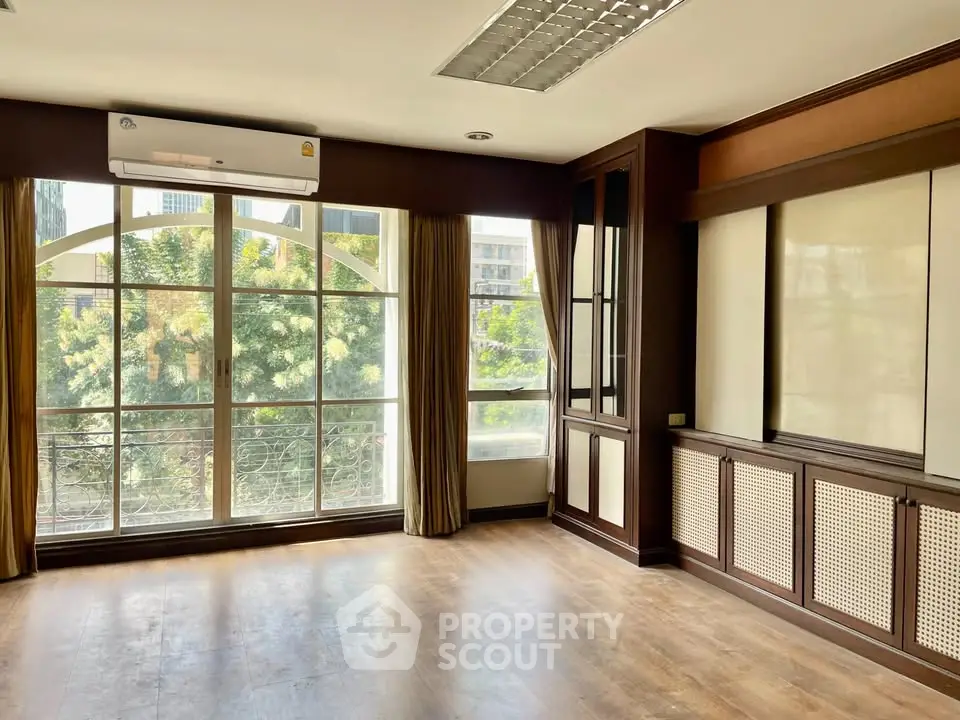 Spacious room with large windows and wooden flooring, perfect for a bright living area.
