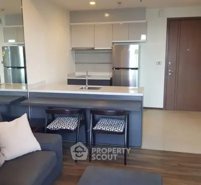 Modern open-layout kitchen with sleek appliances and cozy seating area in a stylish apartment.
