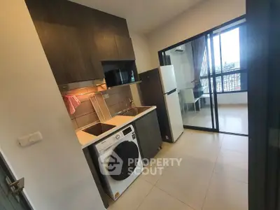 Modern kitchen with washing machine and fridge, open layout to dining area with city view.