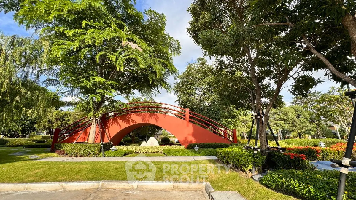 Stunning garden with a red arched bridge and lush greenery, perfect for tranquil living.