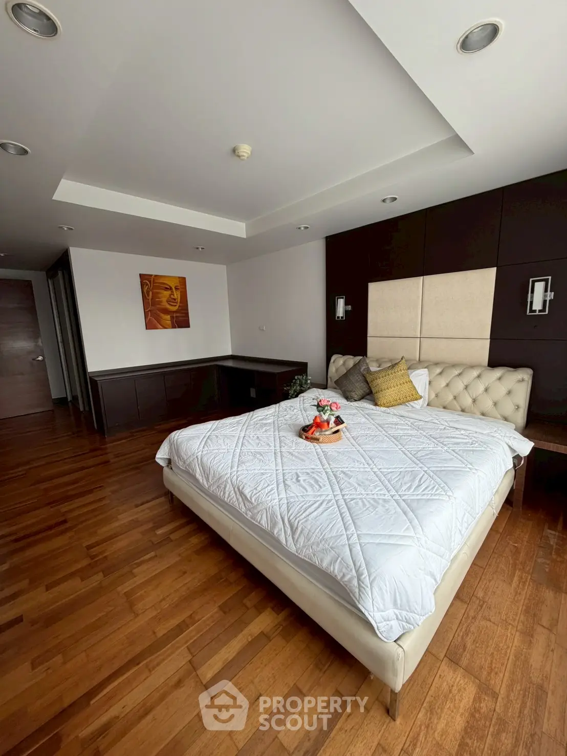 Spacious bedroom with elegant decor and wooden flooring in modern apartment.