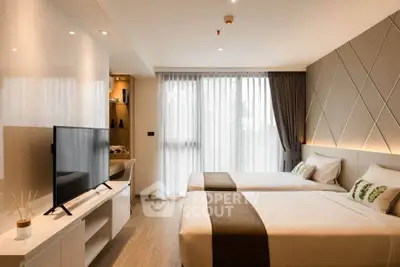 Modern bedroom with twin beds, stylish decor, and natural light from large window.