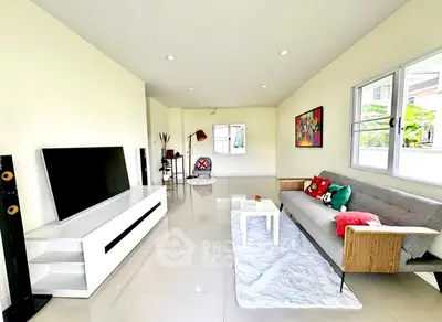 Spacious modern living room with sleek furniture and large TV, perfect for relaxation.