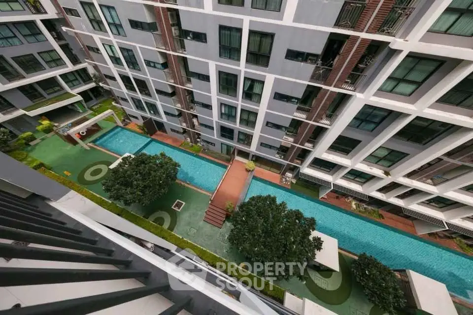 Stunning aerial view of modern apartment complex with luxurious pool and lush greenery.