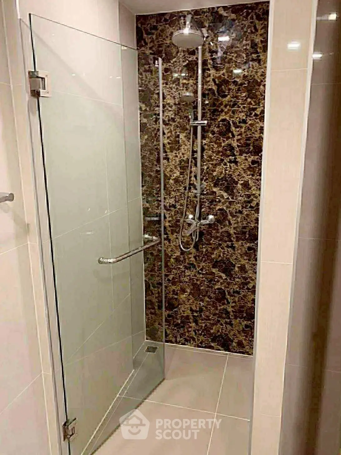 Modern bathroom with glass shower enclosure and elegant marble wall design.